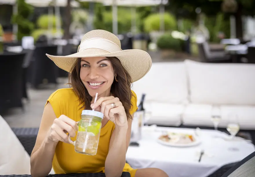 Dame trinkt Getränk auf Terrasse im Vitalhotel.