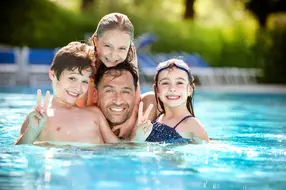 Vater mit 3 Kindern gemeinsam im Pool im Vitalhotel. Vater mit 3 Kindern gemeinsam im Pool im Vitalhotel.